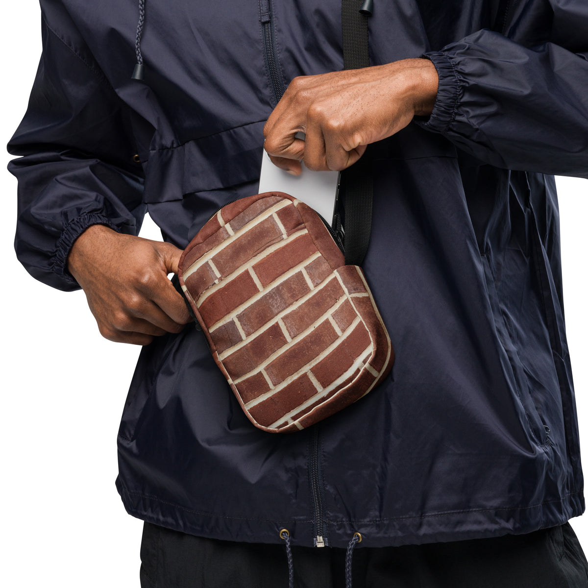 Brick crossbody bag worn at the hip, phone being slipped into the front pocket