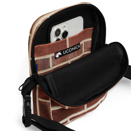 Brick crossbody bag open, phone inside the padded interior beside the Uconica label